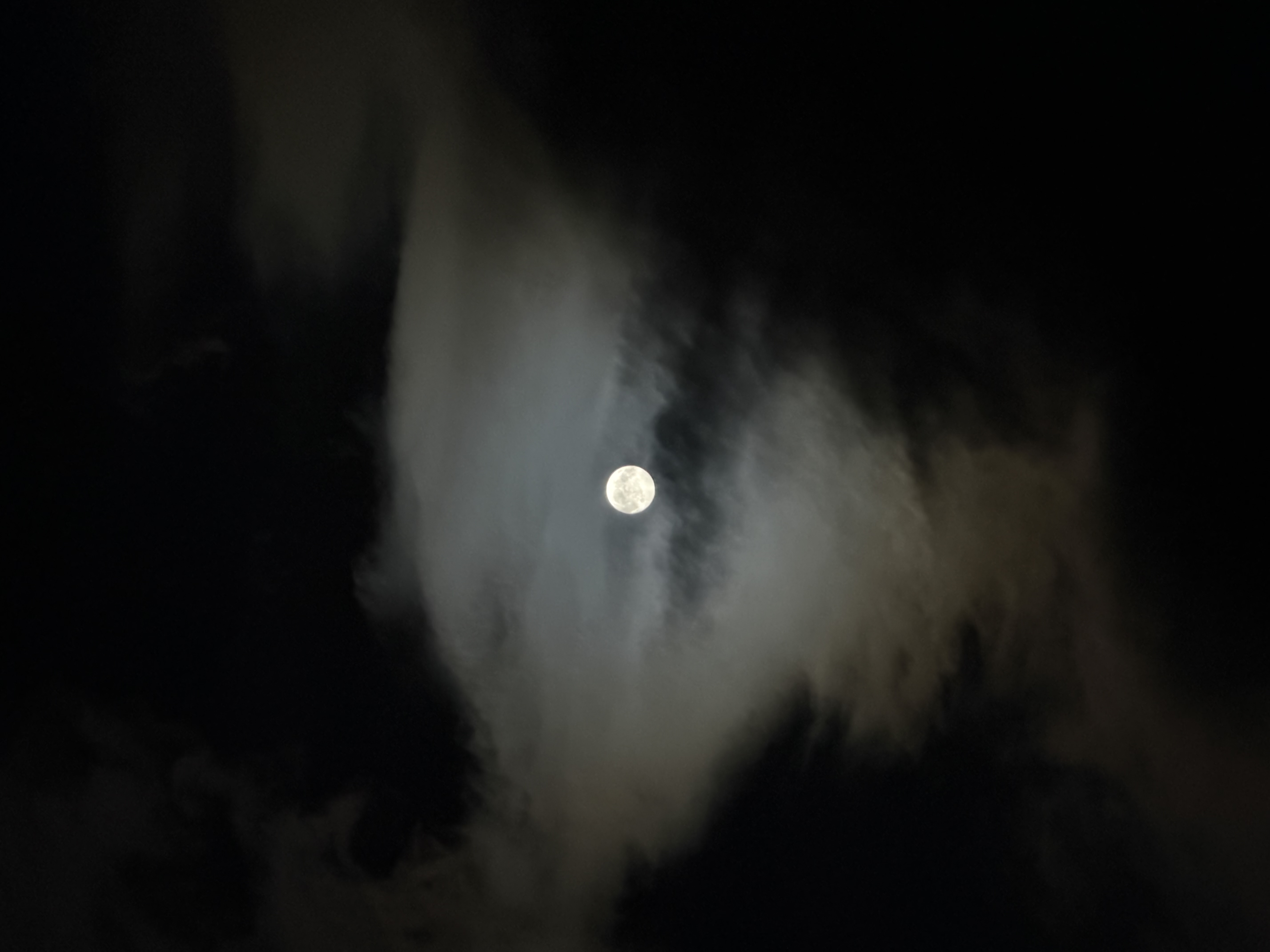 A bright moon in a dark cloudy sky