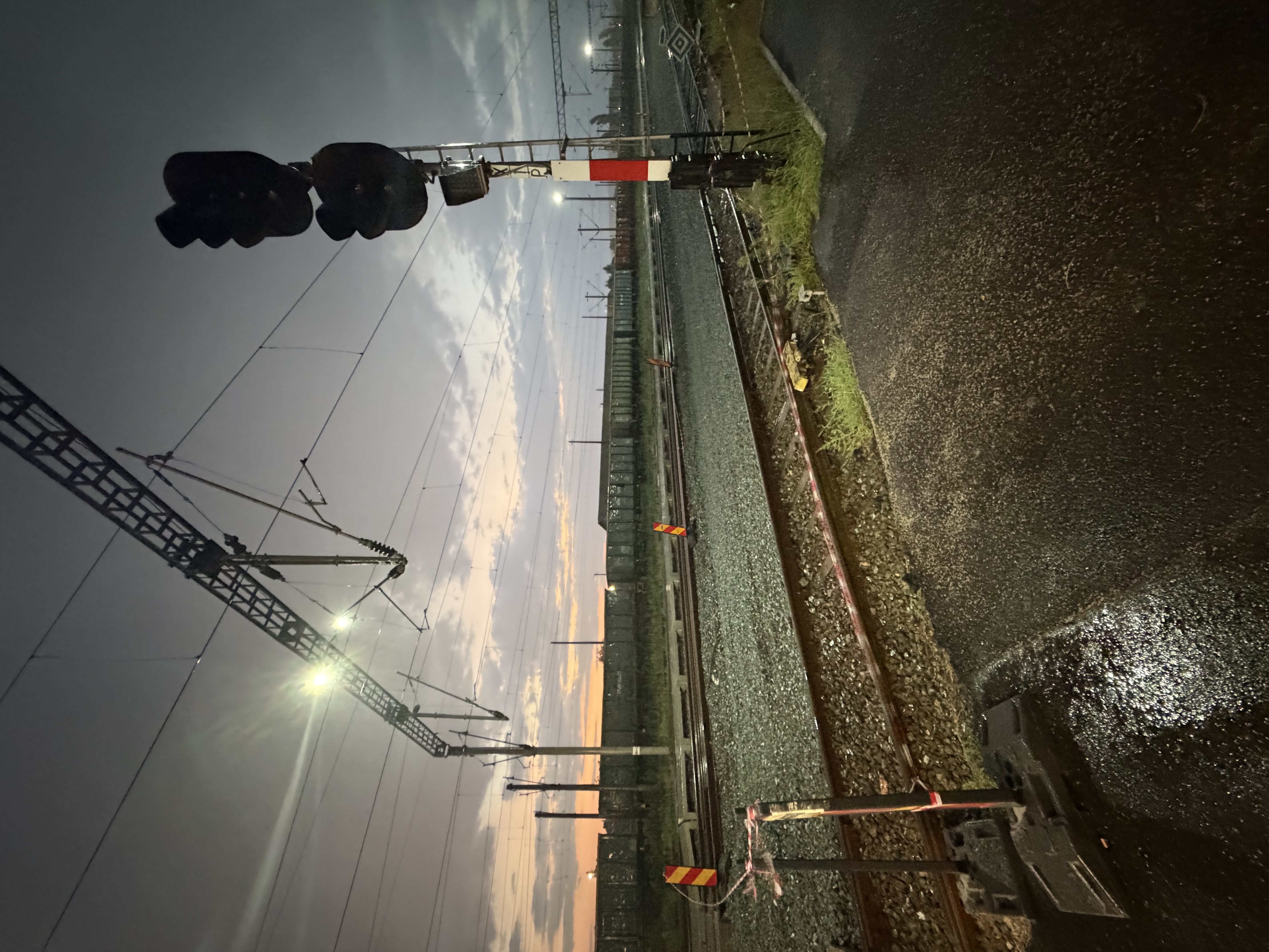 Railway tracks and a signal at dusk, wet after rain